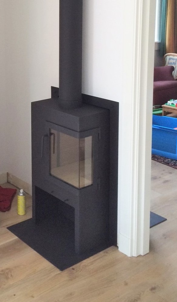 Een in de muur geplaatste doorkijk kachel met deur om de hoek